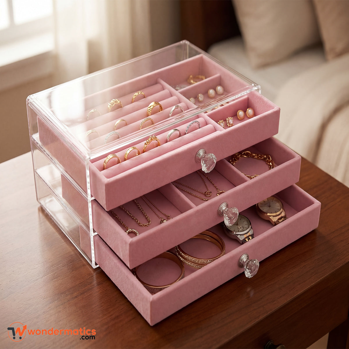 Pink jewelry organizer with clear acrylic top on a wooden surface