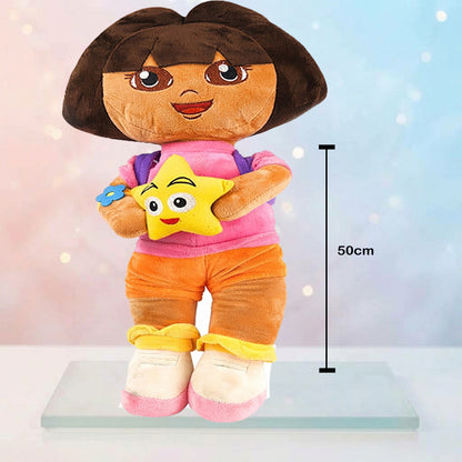 A Dora the Explorer plush doll standing on a clear display base, holding a yellow star toy, with a vertical size marker indicating 50cm. The background is a soft pastel gradient with light bokeh effects.