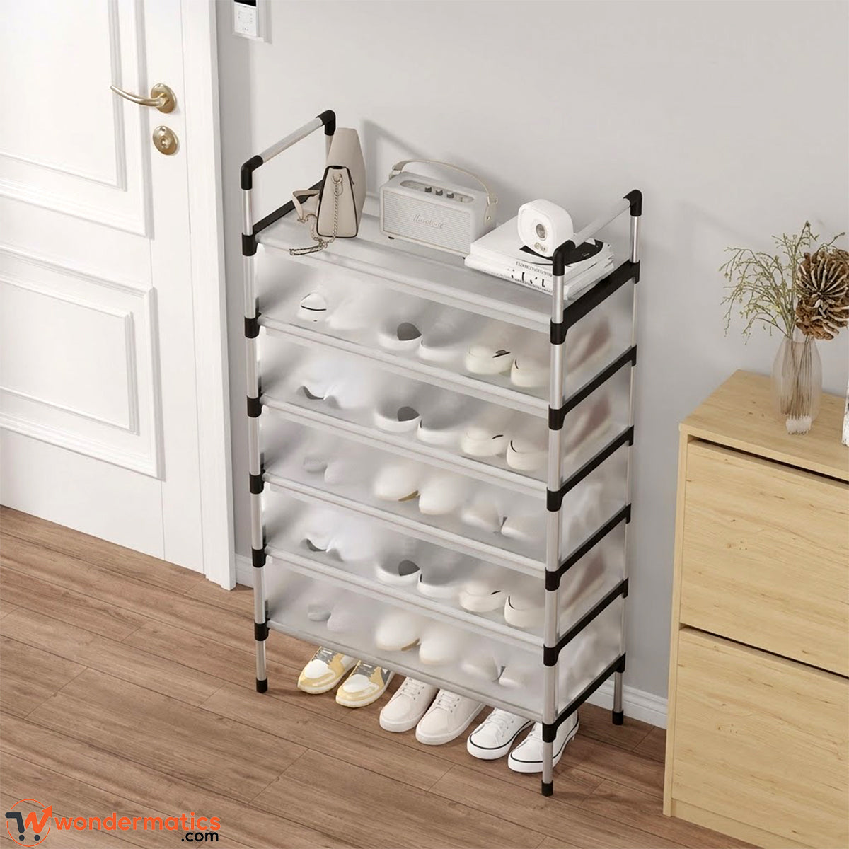 A 6-tier plastic shoe rack with a silver metal frame and black corner brackets, shown in a home entryway next to a white door and wooden cabinet.
