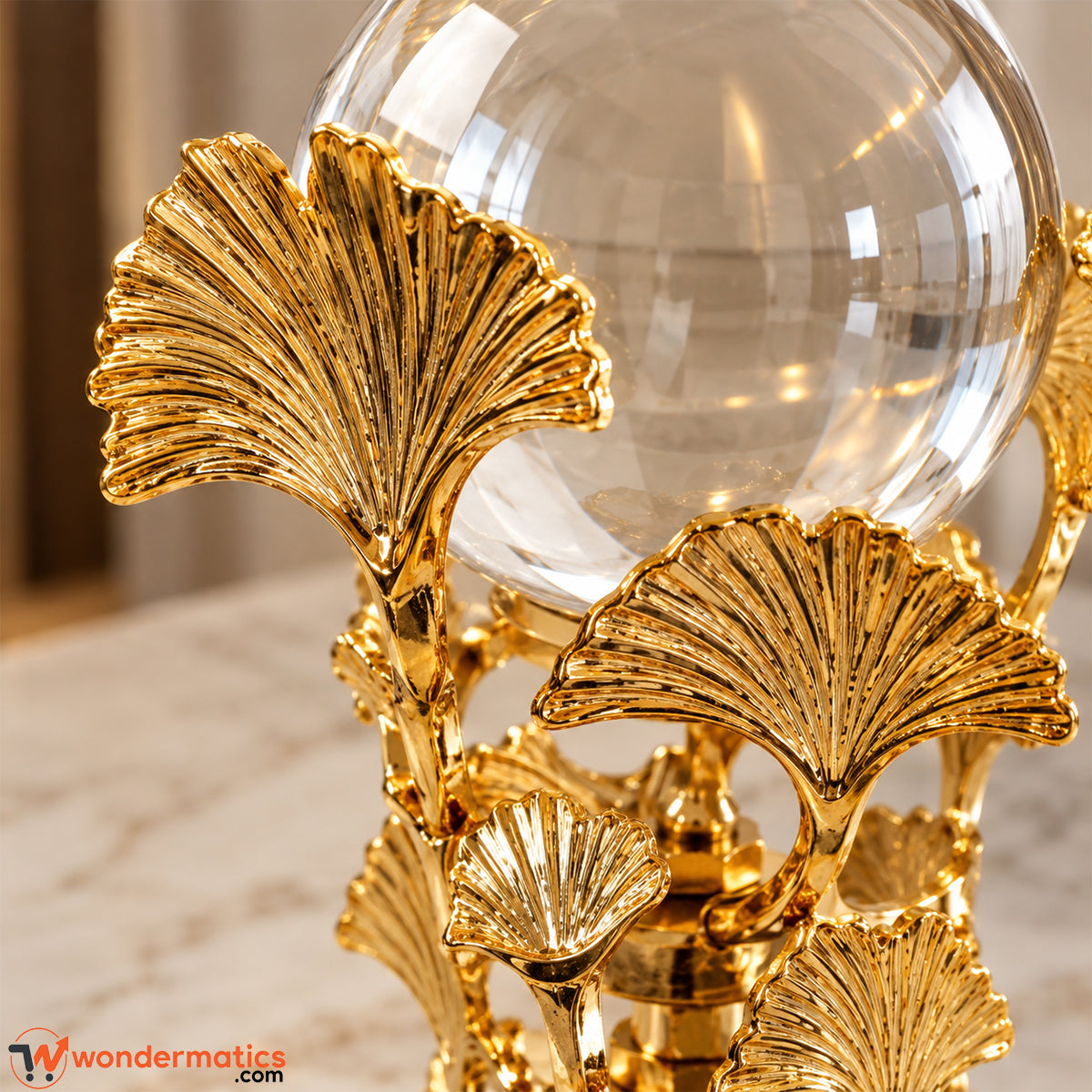 Close-up of ribbed golden metal ginkgo leaves supporting a crystal ball