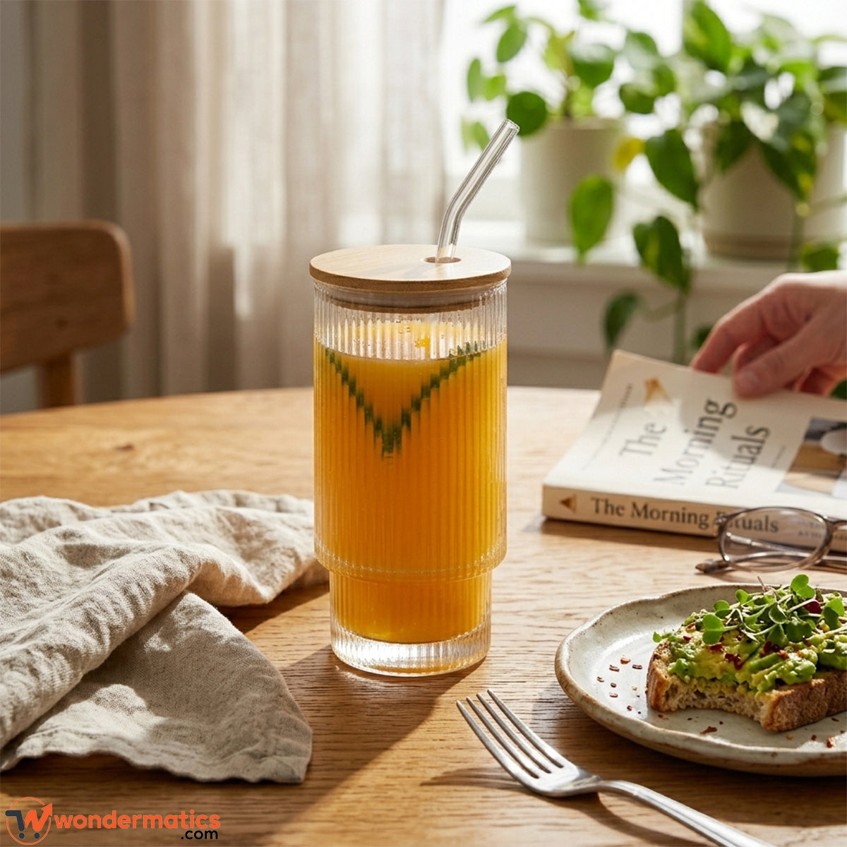 Woman holding ribbed glass tumbler with iced coffee and bamboo lid in a cozy home setting