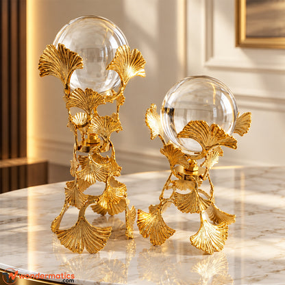 Two golden ginkgo leaf crystal ball showpieces in tall and short sizes on a white marble table