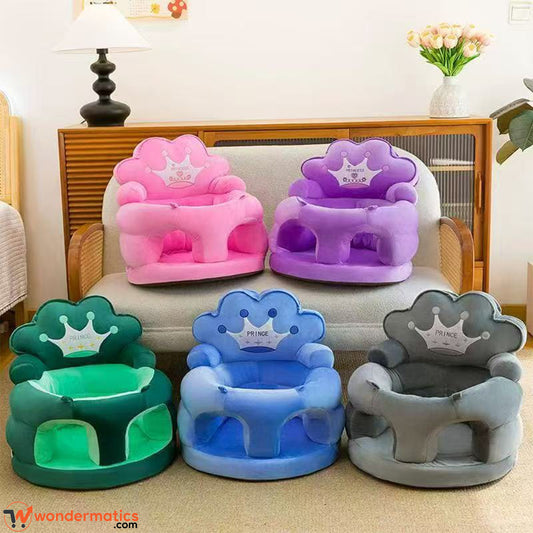 Four cloud-shaped prince and princes baby support plush chairs in pink, purple, green, and blue, along with one gray chair, arranged on and in front of a light-colored sofa in a living room setting.