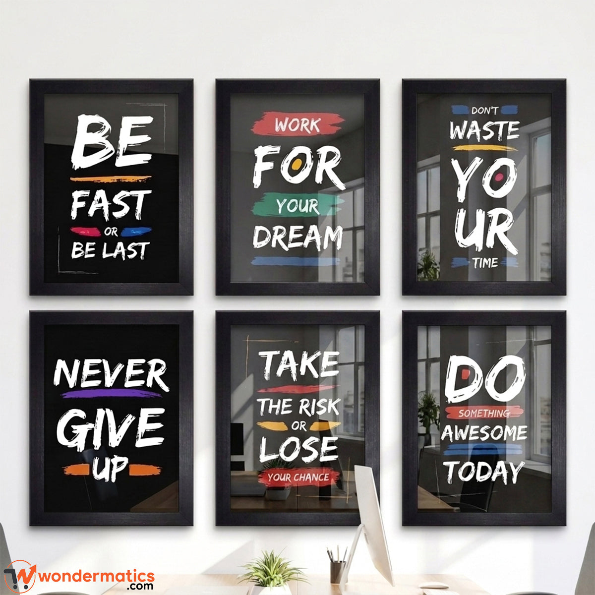 Six framed motivational wall art prints arranged in a 2x3 grid on a white wall above a desk. The prints feature bold white text on black backgrounds with colorful accents and phrases like 'BE FAST OR BE LAST,' 'WORK FOR YOUR DREAM,' 'NEVER GIVE UP,' 'TAKE THE RISK OR LOSE YOUR CHANCE,' 'DO WHAT MATTERS,' and 'DO AWESOME TODAY.