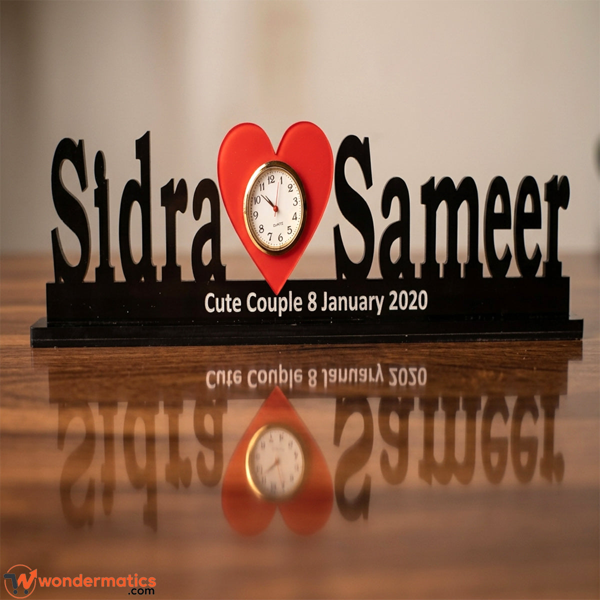 Black acrylic table clock personalized with a name on either side of a heart-shaped clock