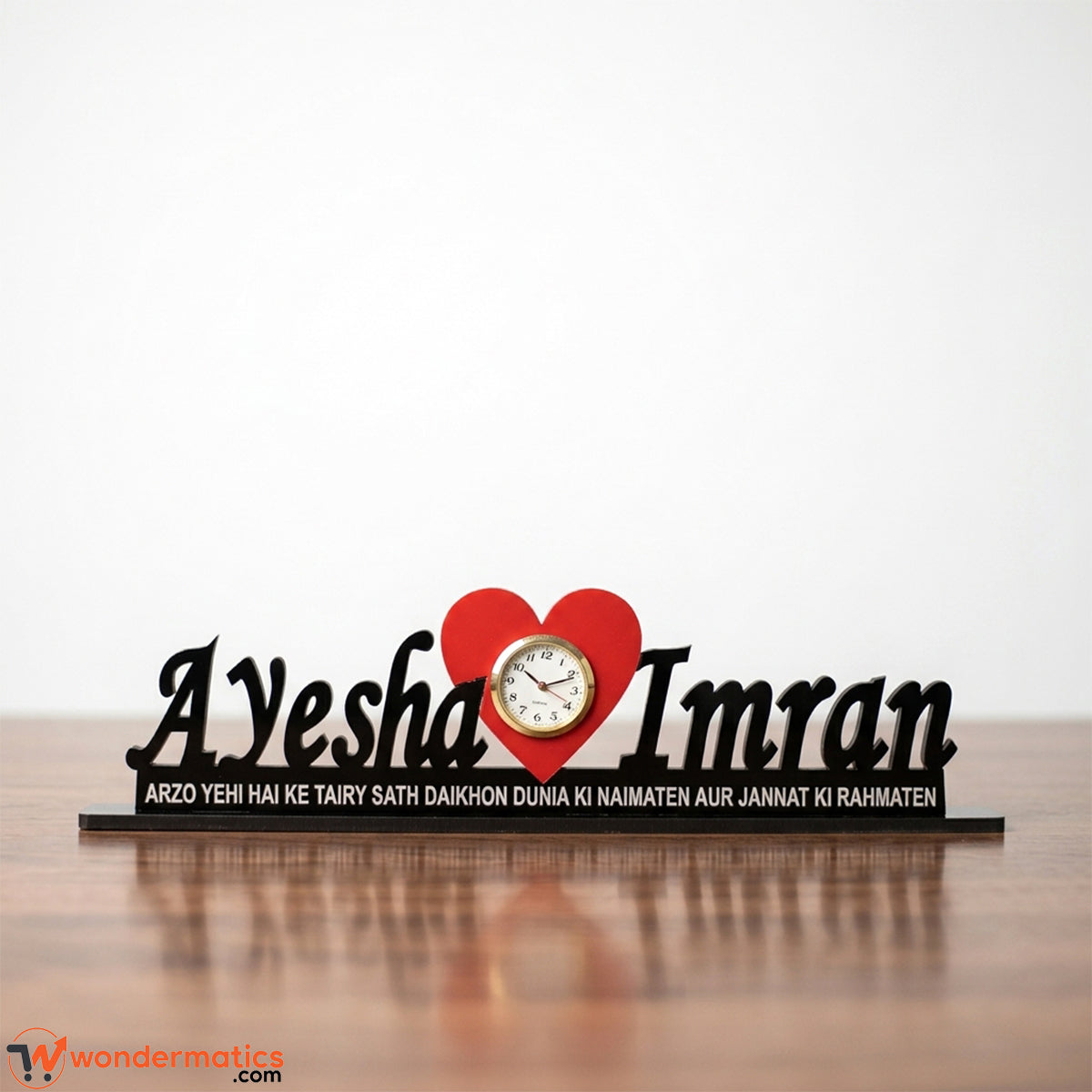 Side angle view of a personalized black acrylic table clock with red heart in the center clock
