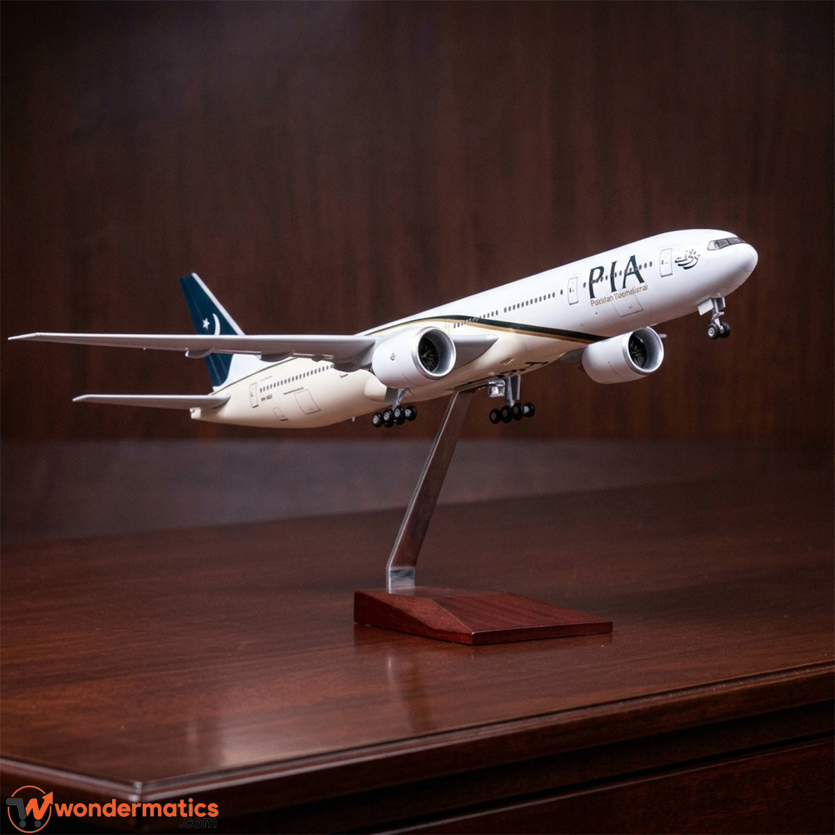 A scale model of a Pakistan International Airlines (PIA) passenger jet displayed on a wooden stand on a polished wooden table, with a dark wood background.