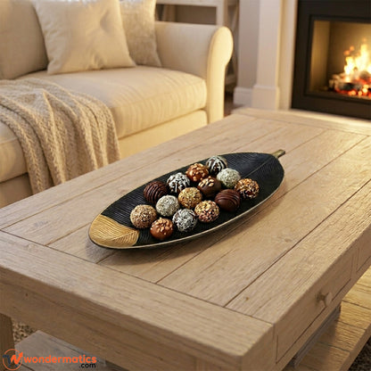 Black and gold wooden leaf tray displayed as decor piece and serving chocolates on a center table
